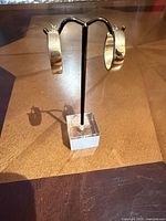Pair of gold hoop earrings on stand, front view