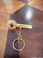 Entire key finder showing floral clip head, chain, and key ring on wood surface
