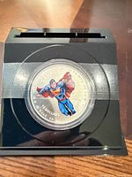 Coloured Superman coin in capsule within acrylic display cube