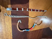 Overview of all three bracelets laid flat: amber link, silver curb chain, leather ID