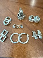 All seven pairs of sterling silver earrings displayed on table