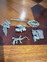 Overview of all six sterling brooches on tabletop