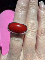 Top view showing red oval cabochon in bezel setting on finger