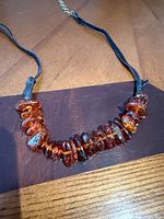 Full necklace showing amber beads on leather cord with extender chain
