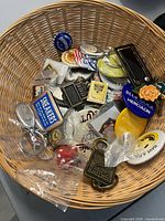 Top view of wicker basket holding mixed vintage pins, badges and keychains