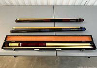 Three cues laid out; hard case open with cue inside