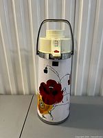 Front view showing poppy floral graphics, pump lid and handle