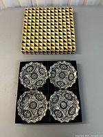 set of four glass ashtrays in open box with patterned lid