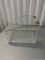 Right side view showing clear acrylic body, angled front, metal hinges on lid