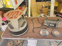 Bench grinder body, step stool, power cord, two loose wheels on table