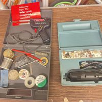 Both open cases: Weller soldering gun kit contents left, Dremel rotary tool kit contents right