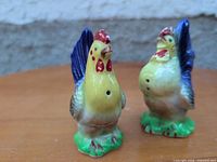 Front view of both ceramic rooster shakers showing color and size
