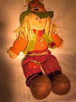 Full view of scarecrow plush doll sitting upright
