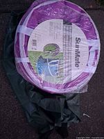 Purple SunMate collapsible garden bag in shrink wrap atop folded green bag