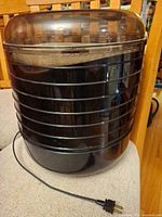 Front view of black cylindrical food dehydrator with power cord