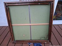 Underside of table showing green panel, leg hinges, and corner protectors