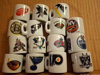 Stack of fifteen miniature NHL team logo ceramic mugs