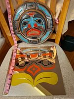 Front view of both pieces showing carved mask and mirror artwork with measuring tape