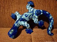 Front view of glazed blue and white ceramic lizard figurine