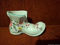 Side view of porcelain boot planter showing floral and bird motif