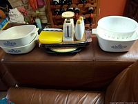 Full lot overview on couch including casseroles, trays, scale, shakers, hot plates, coaster set