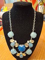 Blue and light blue glass stone bib necklace on display bust