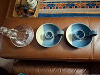 Overview of three chambersticks on sofa: one glass, two ceramic
