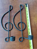 Front view of both wrought iron treble clef sconces with tape measure for scale