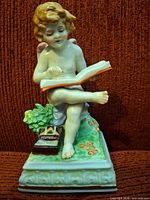 Front view cherub reading book on plinth