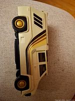 Side view showing cream body, gold stripes, wheel detail