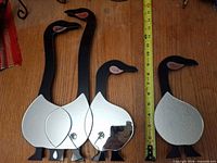 Front view of three goose wall mirrors showing black necks, mirrored bodies, copper beaks, tape measure for scale