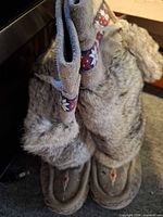 Front view of boots standing upright showing suede base, rabbit fur shafts, patterned band, lace ties and beadwork