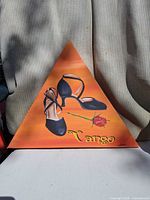 Orange triangular canvas with black tango shoes, rose and “Tango” text