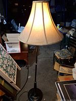 Full view of bronze floor lamp lit with beige shade