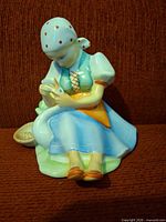 Front view of seated girl figurine holding orange bird, showing colors and pose