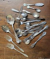 Top view of all silverplate utensils spread on wooden surface