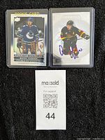 Both autographed Quinn Hughes cards side by side in protective sleeves