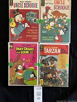 Four comics laid flat showing titles Uncle Scrooge, Huey Dewey and Louie, Tarzan