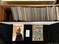 Open long box filled with comics plus two sample issues in front