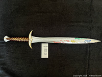 Full view of signed replica sword on black background