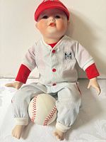 Full view of doll seated with baseball