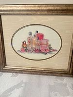 Framed still life print showing perfume bottles and roses