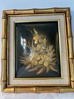 Front view showing gold orchid arrangement, mat and bamboo-style frame