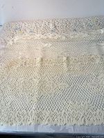 Full view of ivory lace crochet textile laid flat