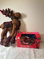 Large plush reindeer beside boxed Snoring Santa figure