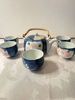 Front view of teapot and five cups displaying overall set