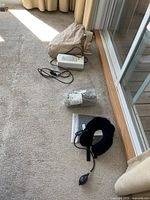 Beige mattress pad, white pump with cord, grey air hose in bag, neck cushion foreground