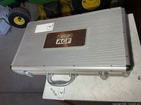 Closed aluminum case with AGF plaque on marble surface