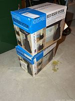 Two sealed boxes of CreativeWare Adjustable Bed Riser System stacked