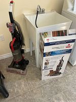 Vacuum standing beside utility sink with box visible